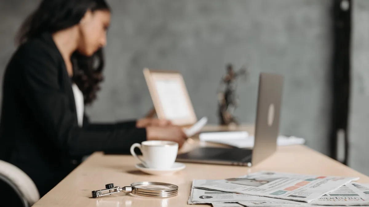 Woman working at her office desk with a laptop and papers, desk posture and back health in everyday work