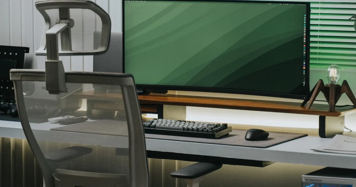 Modern desk setup with a large monitor and ergonomic chair, a neutral workstation for healthy desk posture