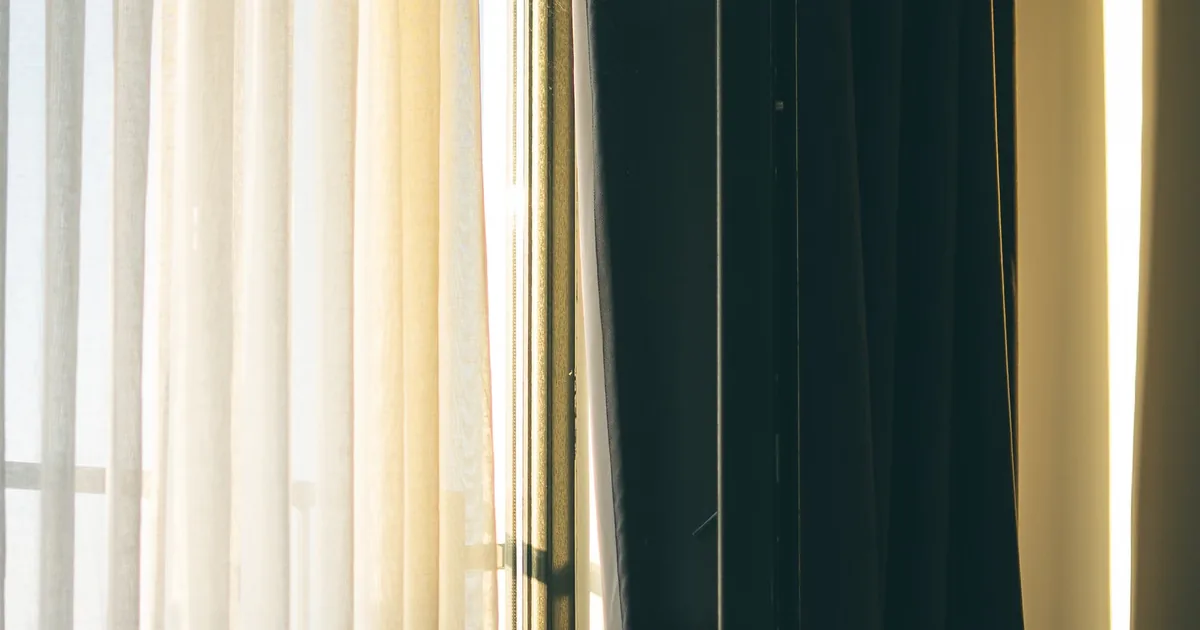 Cozy bedroom with morning light streaming through the curtains, part of the evidence-based perimenopause sleep fixes