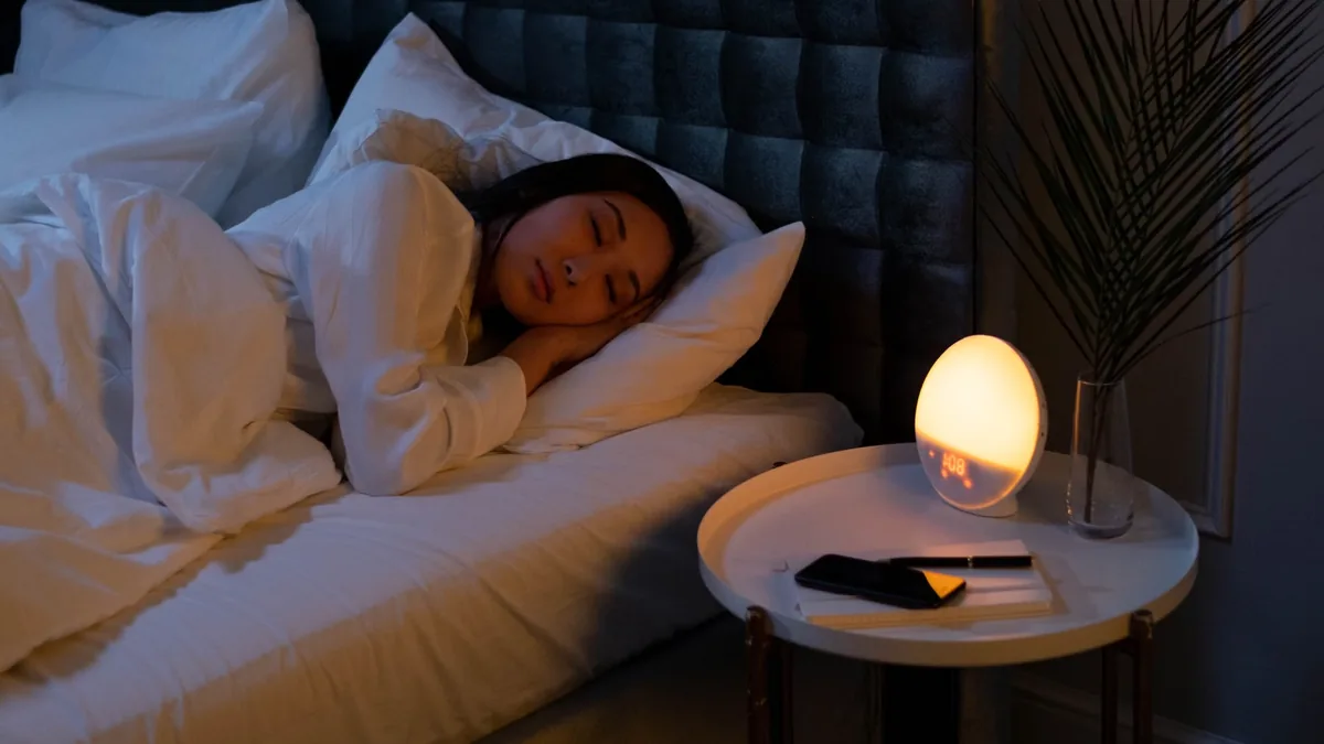 Woman sleeping peacefully in a dark bedroom with a soft night light, perimenopause sleep changes in midlife